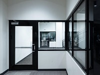 Hallway with black glass doors and a white floor, showcasing fire-rated glazing used in emergency exit designs.